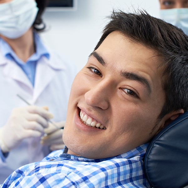 A man at the dentist waiting for his tooth extraction while smiling